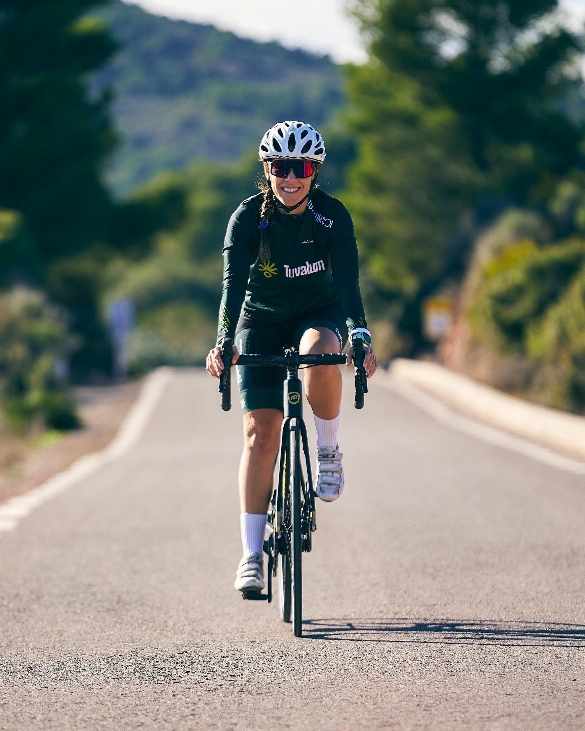 A vibrant image of a woman cycling on a sunny road, embodying active outdoor lifestyle.